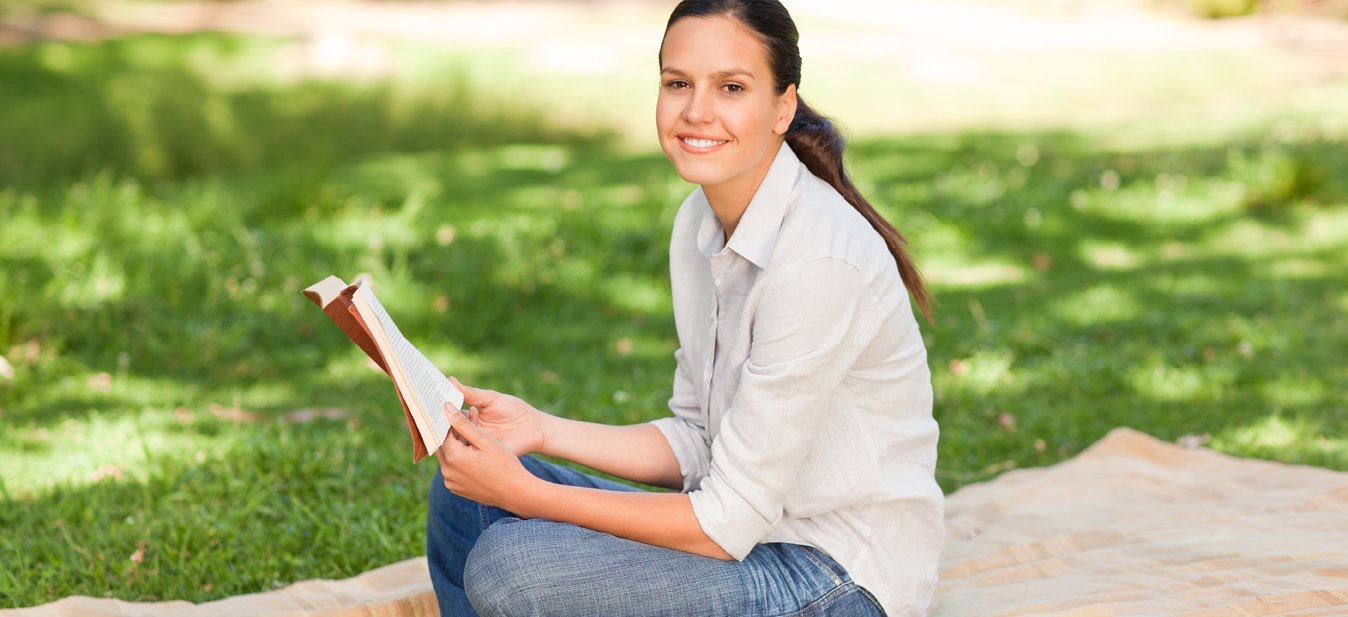 adult reading book outside